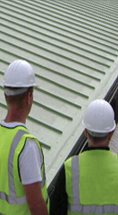 Two Braedale Roofing operatives in hard hats inspecting a standing seam roof